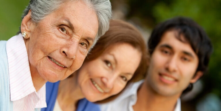 Elderly Woman Smiling with Family Members Outdoors During Daylight at an Assisted Living Facility