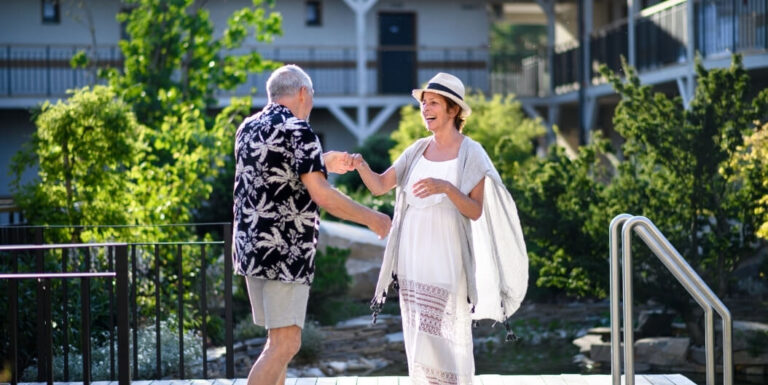 Elderly Couple Enjoying a Sunny Summer Day by the Pool at Assisted Living Facility