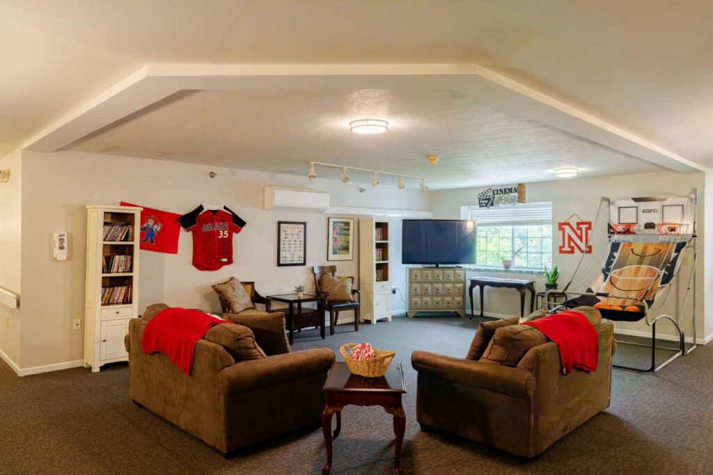 Spacious Common Room With TV Seating And Sports Décor At Assisted Living Facility