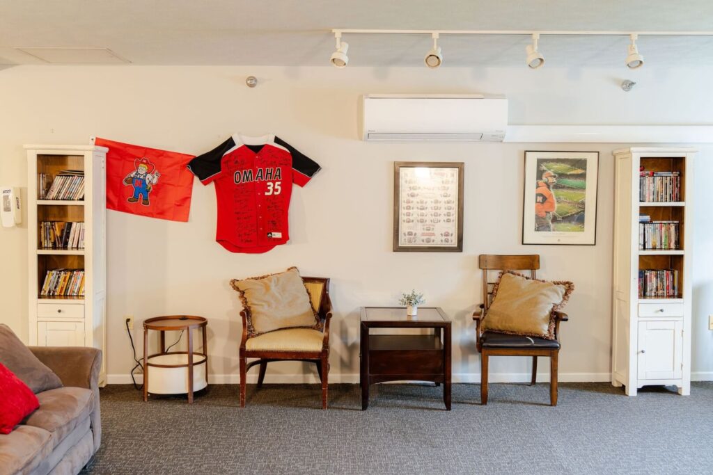 Cozy Lounge Area With Sports Memorabilia And Bookshelves At Assisted Living Facility